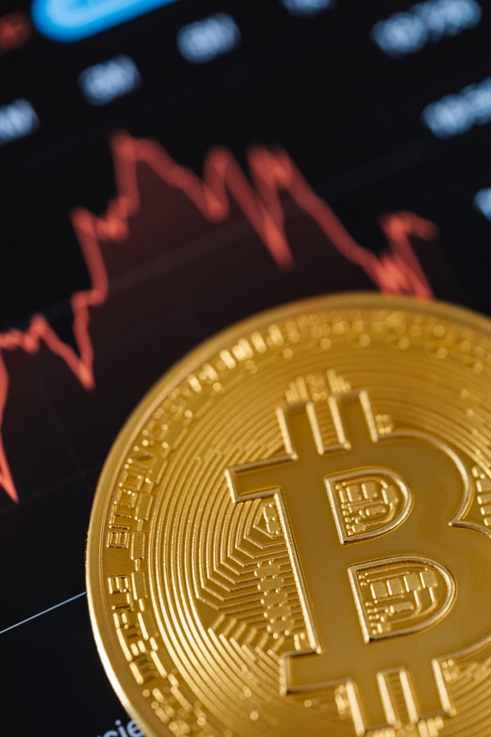 Close-up of a Gold Bitcoin Coin with Graphs in the Background